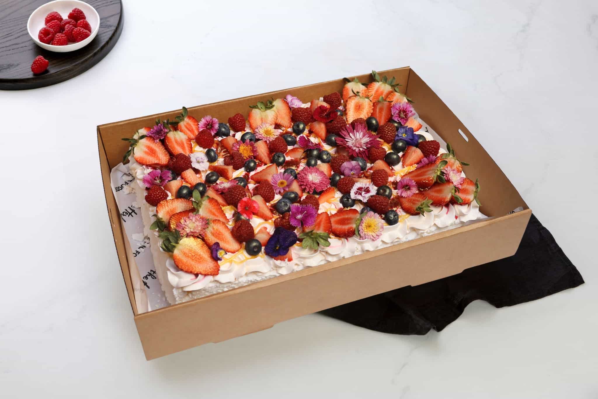 Pavlova Slab Floral Pavlova floral pavlova topped with whipped cream, mixed fresh berries, edible flowers and gold dust